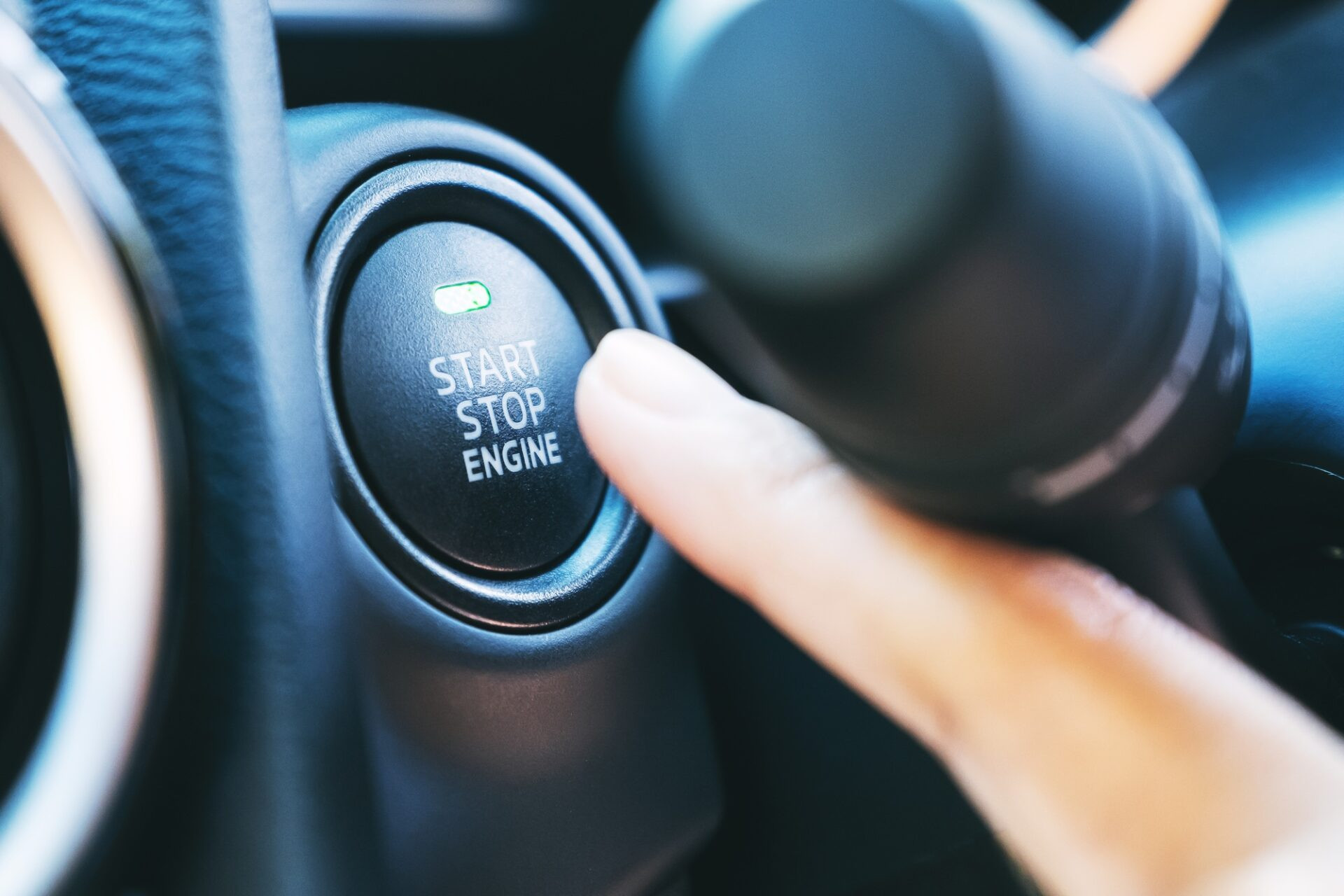 Image de gros plan d'un doigt en appuyant sur un bouton de démarrage du moteur dans une voiture