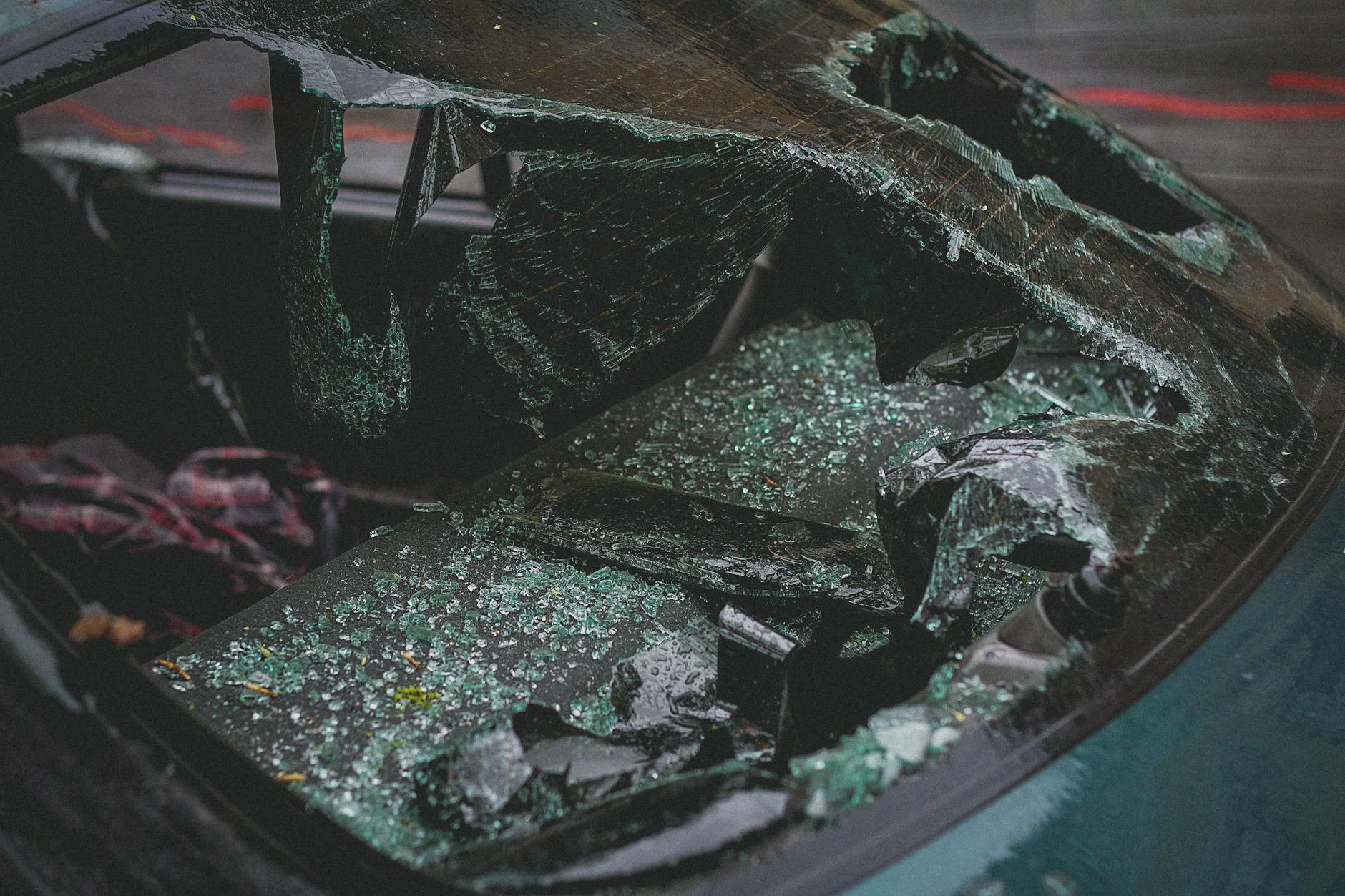Vue détaillée du pare-brise brisé après accident, mettant l'accent sur les dommages et le verre brisé.