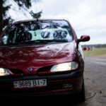 Gros plan d'un pittoresque Renault rouge sur une route rurale pendant la journée.
