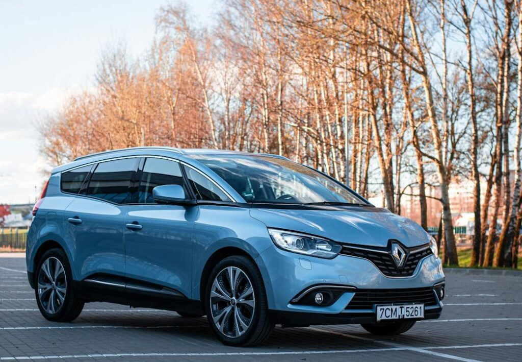 Une voiture Blue Renault brillante garée dans un terrain vide avec des arbres nus en arrière-plan.
