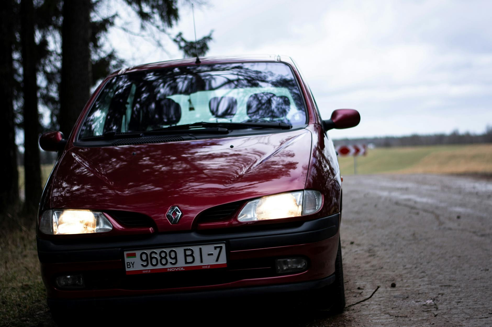 Gros plan d'un pittoresque Renault rouge sur une route rurale pendant la journée.