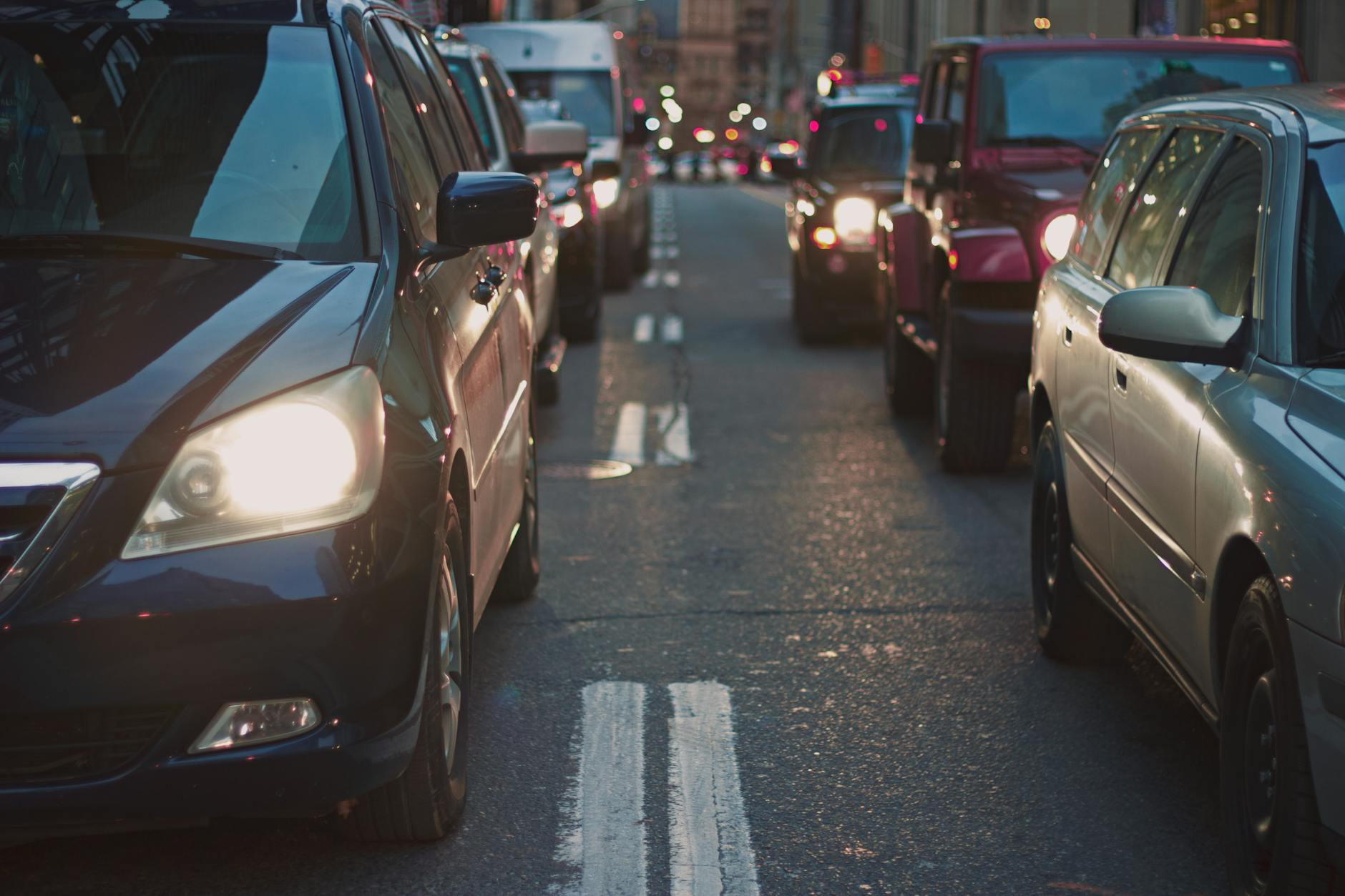 Une rue de la ville congestionnée bordé de voitures coincées dans la circulation au crépuscule, présentant une vie urbaine.