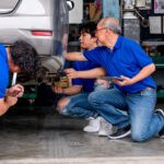 Les travailleurs de la tête et du garage aident à résoudre le problème de la voiture dans la zone de travail.