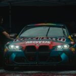 Vue de face d'une voiture de course BMW M4 arborant la marque Red Bull Motul sous un éclairage tamisé.